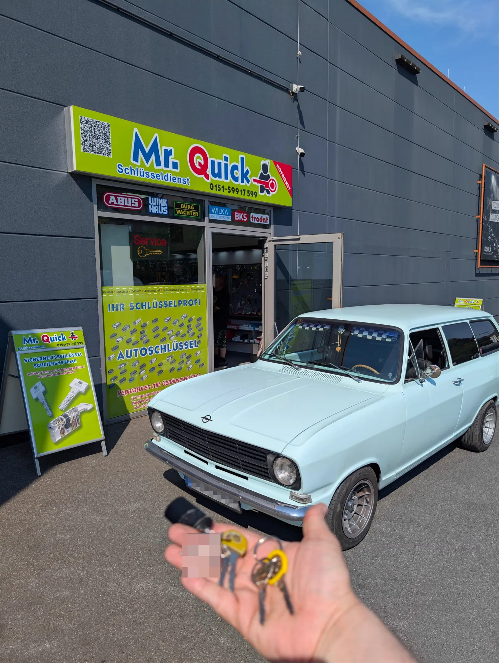 Frisch angefertigter Oldtimerschlüssel vor einem klassischen Opel bei Mr. Quick
