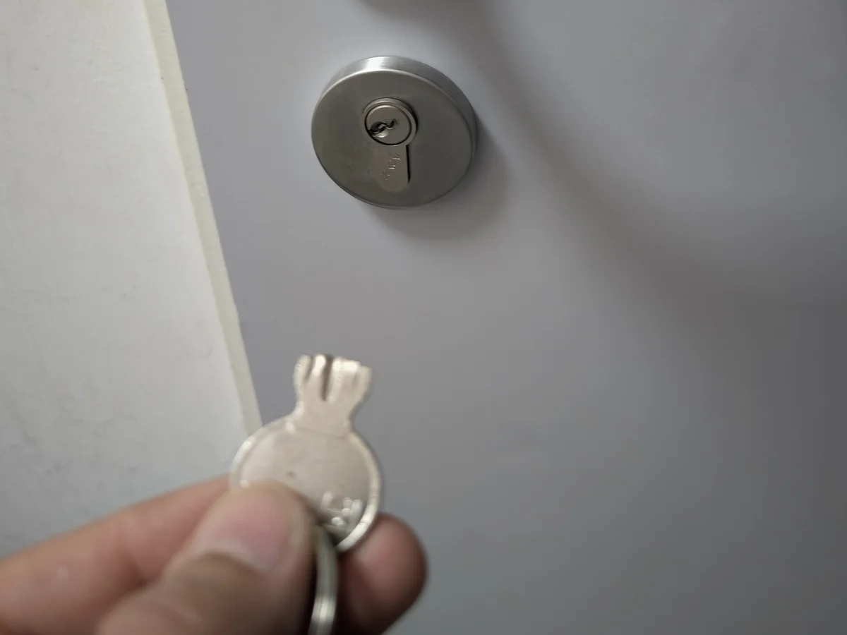 Abgebrochener Schlüsselkopf in der Hand vor einem Schließzylinder mit steckendem Schlüssel